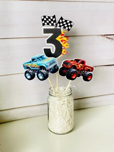 a cupcake topper with cars on it sitting in a mason jar filled with rice