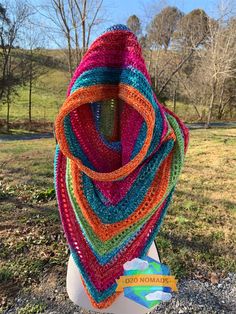 a multicolored crocheted shawl sits on a mannequin