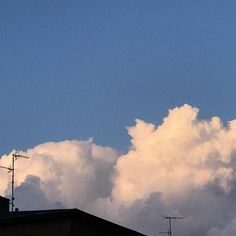 an airplane is flying high in the sky above some buildings and clouds that are mostly white