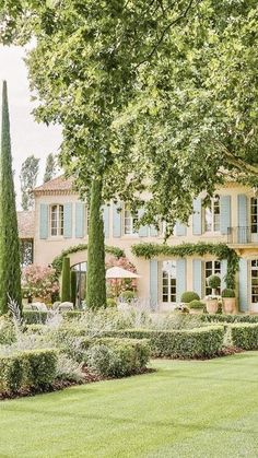 a large house with many trees and bushes in front of it, surrounded by lush green grass