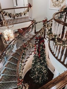 a christmas tree on the top of a spiral staircase with lights and garlands around it