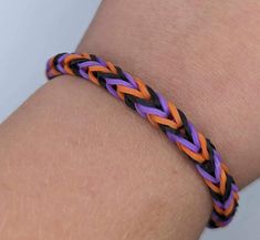 an orange, purple and black braided bracelet on someone's arm or wrist