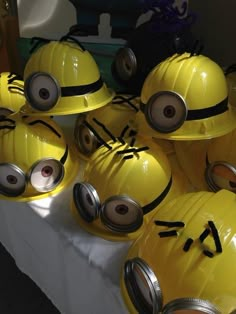 several yellow helmets with eyes and faces drawn on them are sitting on a white table