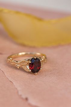 a close up of a ring with a red stone in it on a pink cloth