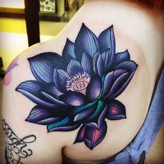 a woman's shoulder with a purple flower tattoo on her left arm and chest