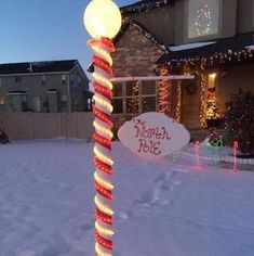 a lighted pole in the middle of a snow covered yard with christmas lights on it