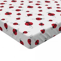 a white sheet with red ladybugs and black dots on the bottom, in front of a white background