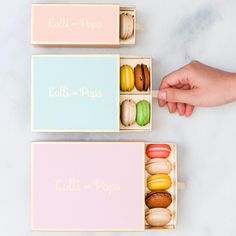 two boxes filled with different types of macaroons on top of a white table