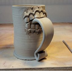 a ceramic mug with teeth on it sitting on a table