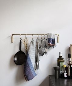 kitchen utensils hanging on the wall next to pots and pans