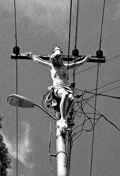 a black and white photo of a man on a cross with wires in the background