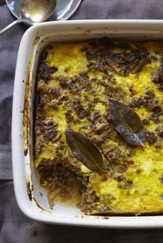 a casserole dish with meat, cheese and other toppings in it on a table