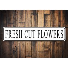 a sign that reads fresh cut flowers on a wooden wall with planks in the background