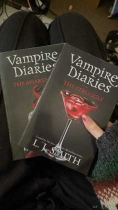 two vampire books sitting next to each other on top of a person's feet