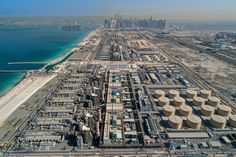 an aerial view of oil storage tanks in the middle of a city near the ocean