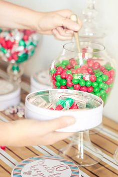 a person scooping candy into a bowl on top of a table with other candies