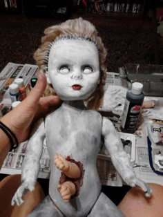 a person holding a doll with white paint on it's body and hands next to the doll