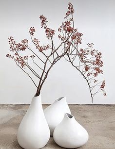 two white vases with red flowers in them on the floor next to each other