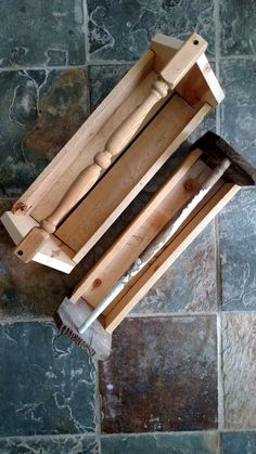 a wooden tool holder with two tools in it on top of a tile floor next to a stone wall