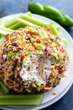 a white plate topped with green beans covered in cheese and other toppings next to celery