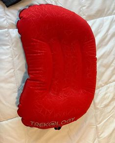 there is a red seat cushion on top of a white bed with the word trekolor printed on it