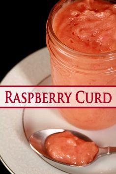 there is a spoon on the plate next to a jar of raspberry curd