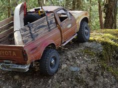 an old pick up truck is parked on the side of a hill in the woods