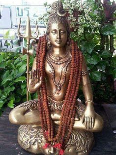 a golden statue sitting on top of a wooden table next to some flowers and greenery