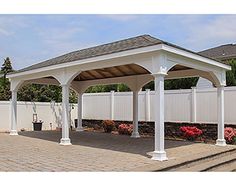 a large white gazebo sitting on top of a brick patio next to a fence