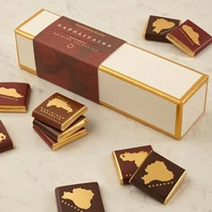 some chocolates are sitting on a table next to a box with gold trimming