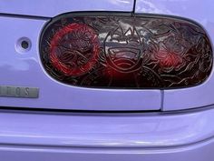 the rear end of a purple car with intricate designs on it's side window