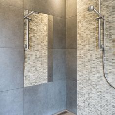 a bathroom with tiled walls and flooring, two shower heads are on the wall