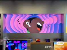 an image of a cartoon character on the wall behind two laptops and a television