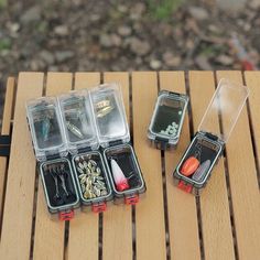 three plastic containers filled with different types of fishing lures and tackle hooks on top of a wooden table