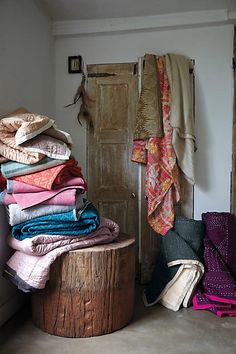 a pile of folded clothes sitting on top of a wooden stump in front of a door