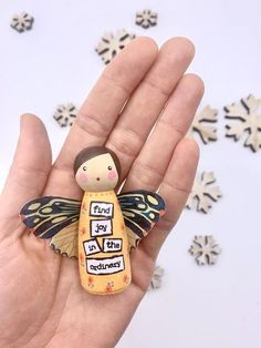 a hand holding a tiny figurine with words on it