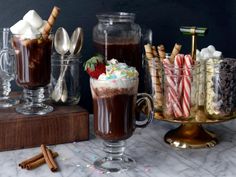 hot chocolate and marshmallows are served in glass mugs with spoons