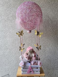 a teddy bear sitting on top of a wooden crate with a pink balloon attached to it