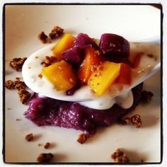 a dessert with fruit and yogurt is on a white plate, ready to be eaten