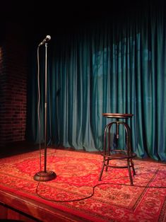 a microphone and stool on a stage with curtains in the background