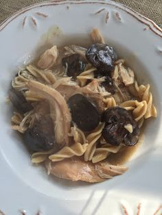 pasta with mushrooms and raisins in a white bowl on a brown tablecloth