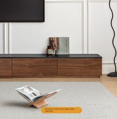 an open magazine laying on the floor in front of a flat screen tv and entertainment center