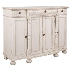 an old white cabinet with three doors and two drawers