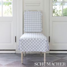 a blue and white checkered chair sitting in front of a door with the words schumacher on it