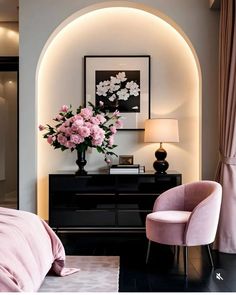 a pink chair sitting next to a black dresser with flowers on it in a bedroom