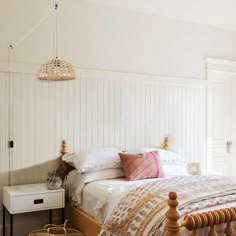 a bedroom with white walls and wooden bed frame, wicker basket hanging from the ceiling