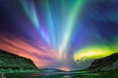 the aurora bore is glowing brightly in the night sky above some mountains and snow covered ground