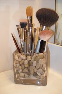 a cup filled with lots of different types of makeup brushes and rocks on top of a counter