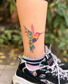 a woman's foot with a colorful bird tattoo on it