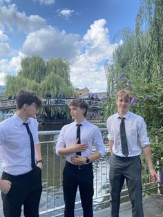 three young men standing next to each other on a bridge